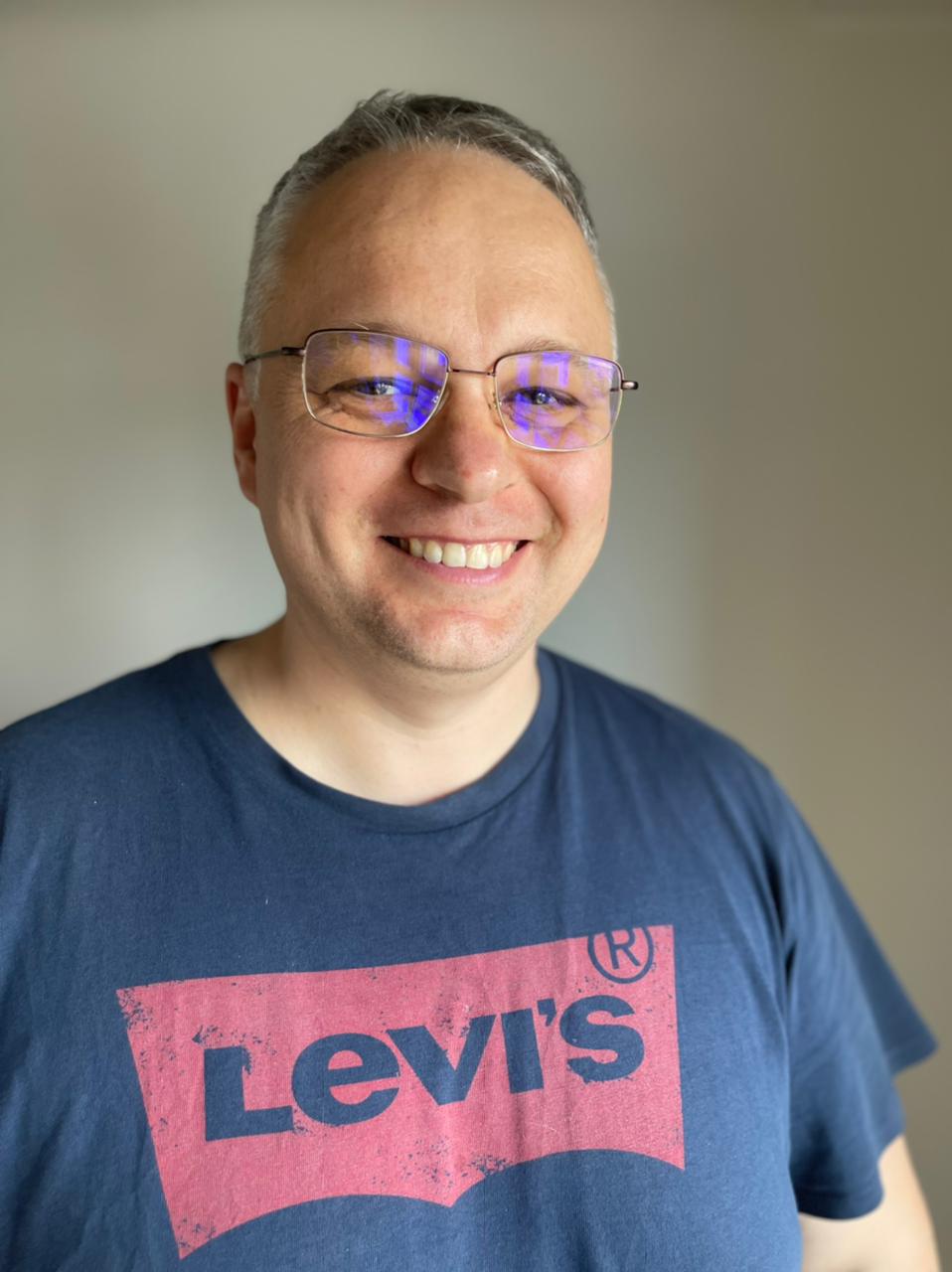 Serhii Riabchuk, smiling man with short hair wearing a blue t-shirt with glasses